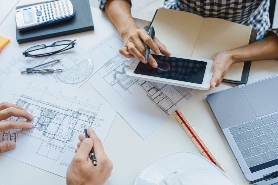 engineer Hand Drawing Plan On Blue Print with architect equipment discussing the floor plans over blueprint architectural plans at table in a modern office